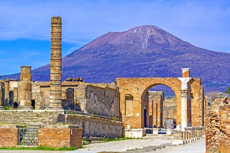 Temple columns and gate with Vesuvius volcano in the background  at the ancient Roman city of Pompeii, Italy