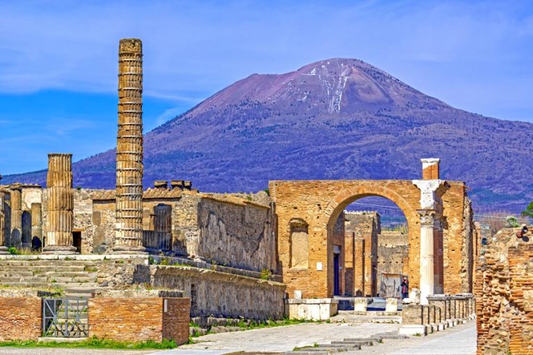 Temple columns and gate with Vesuvius volcano in the background at the ancient Roman city of Pompeii, Italy